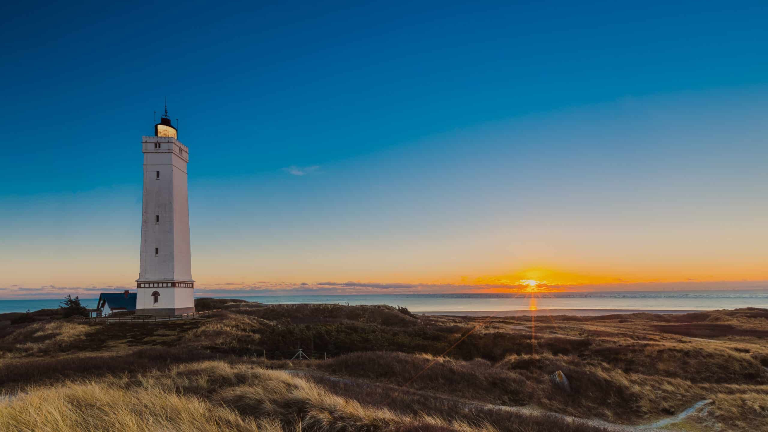 Ein Leuchtturm steht auf einem Hügel mit Blick auf den Ozean.