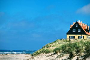 Ein Haus steht auf einer Sanddüne in der Nähe des Ozeans.