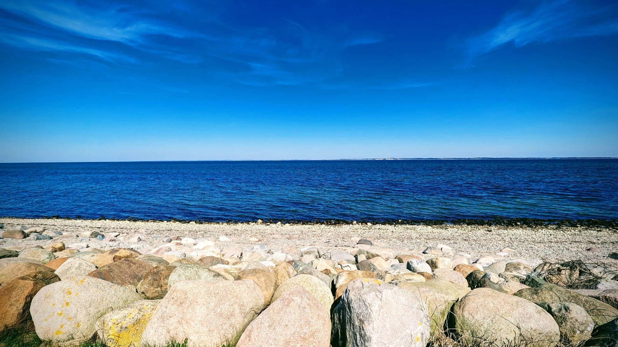 Ein Strand mit Felsen und blauem Himmel.