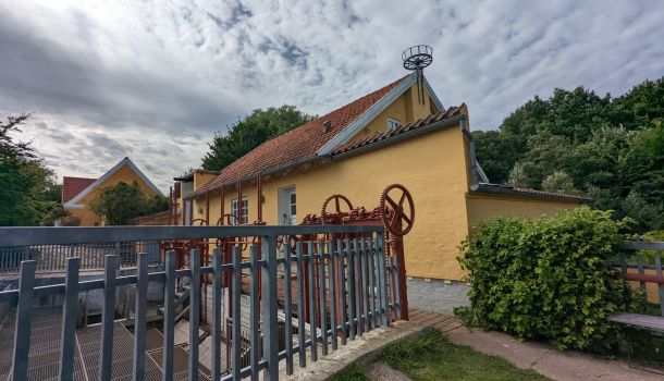 Ein gelbes Haus mit einem Metallzaun im Hintergrund.