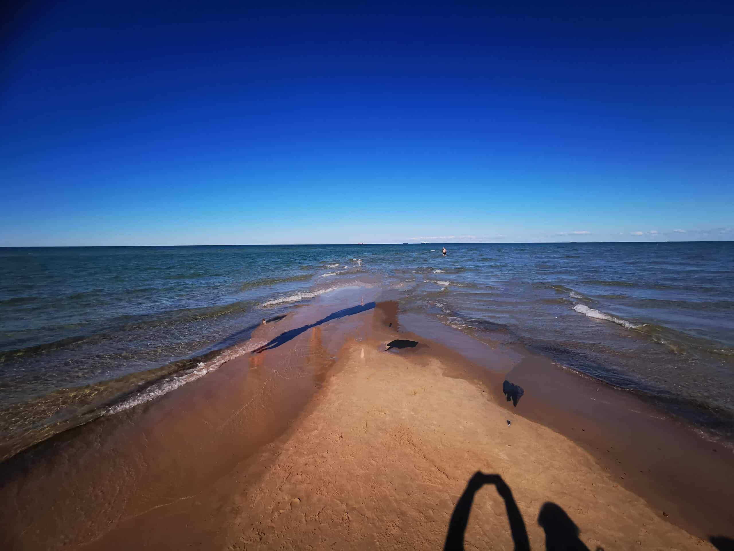 Eine Person steht an einem Sandstrand in der Nähe des Ozeans.