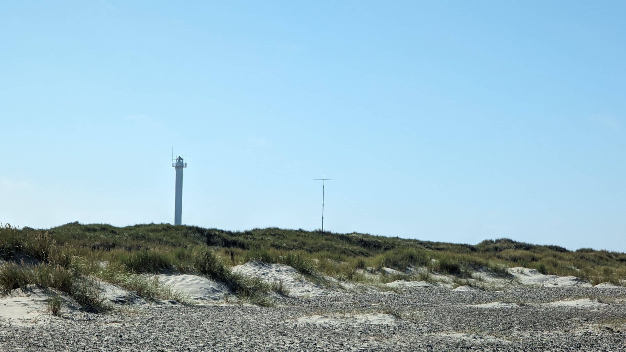 Ein Leuchtturm an einem Sandstrand.