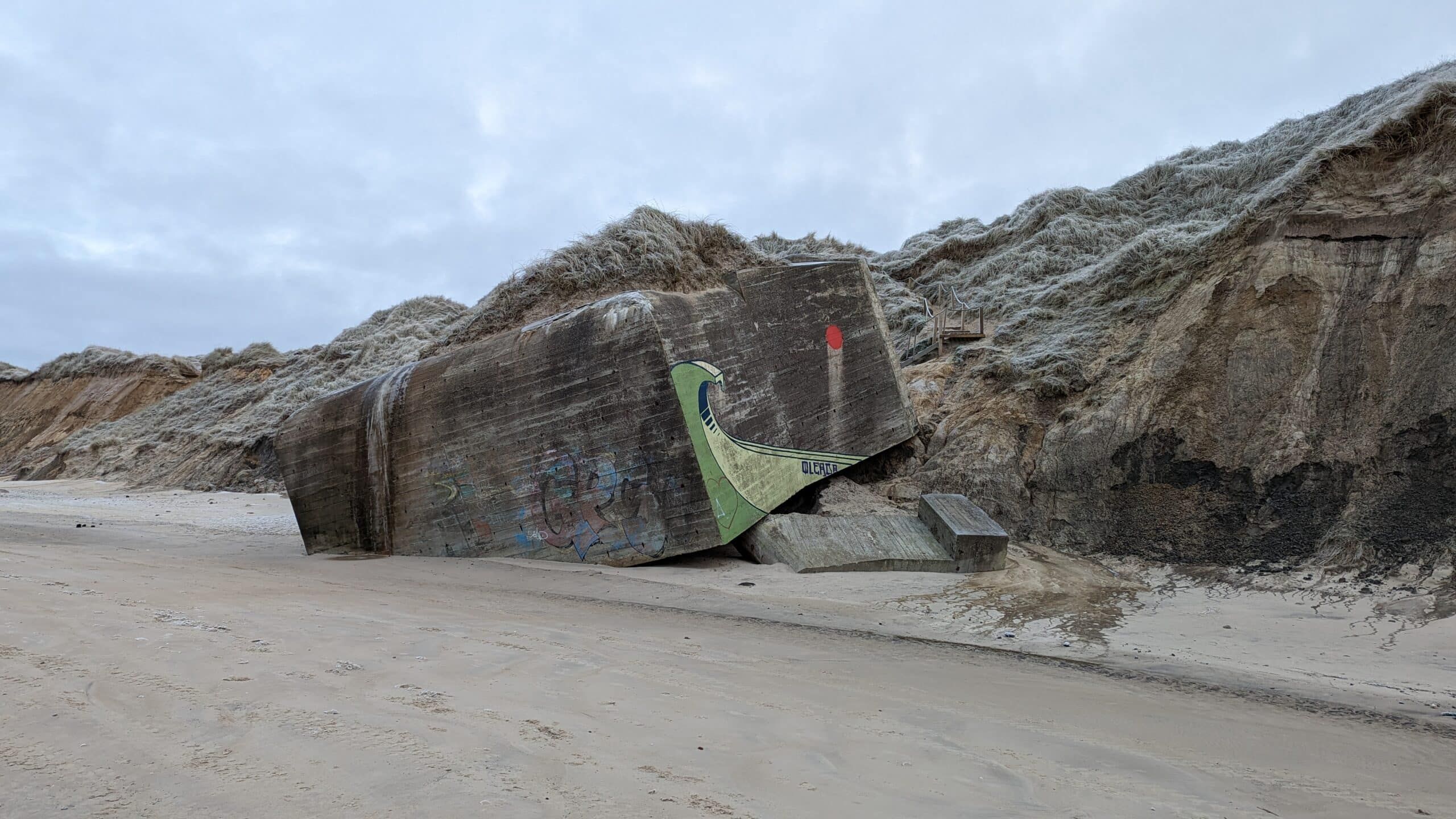 Ein großer Felsen am Strand mit Graffiti darauf.