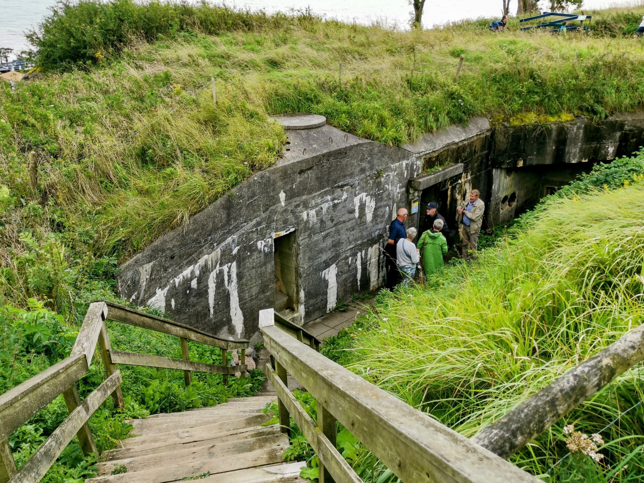 Eine Gruppe von Menschen geht einen Hügel hinauf zu einem Bunker.