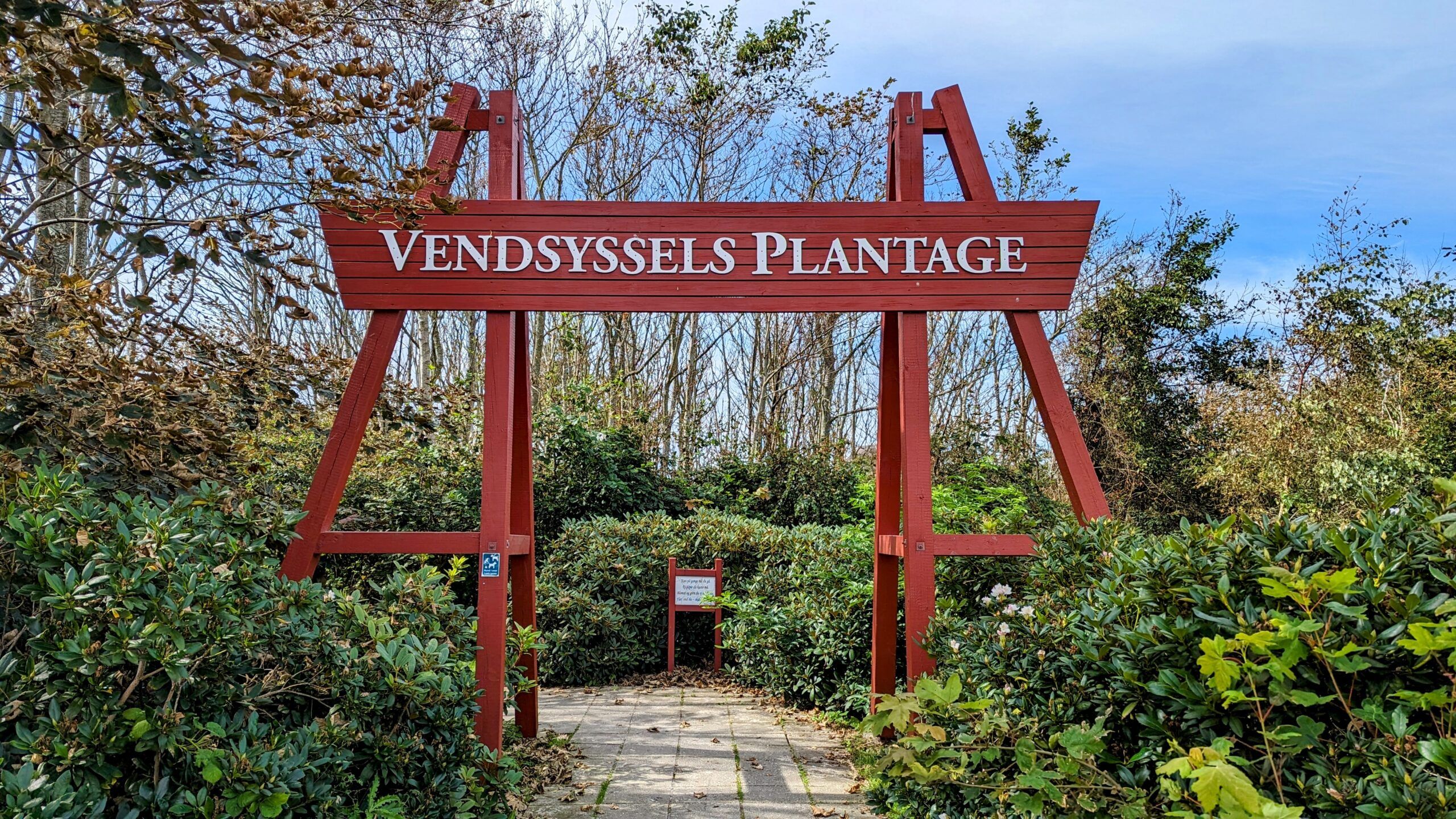 Ein Schild mit der Aufschrift Vandessela Plantage vor Büschen.