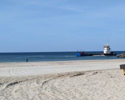Ein Boot liegt im Wasser in der Nähe eines Sandstrandes.