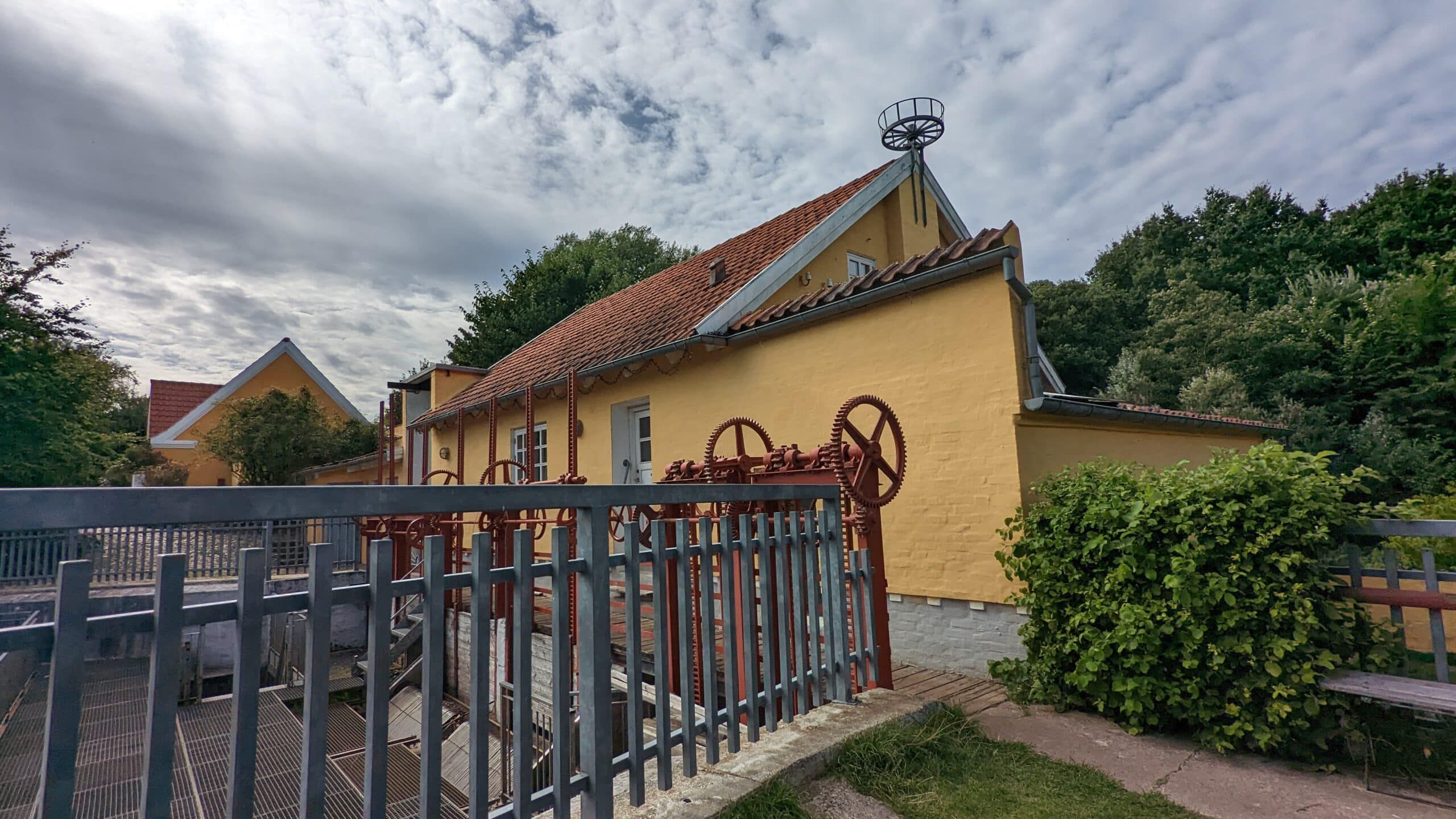 Ein gelbes Haus mit einem Metallzaun im Hintergrund.