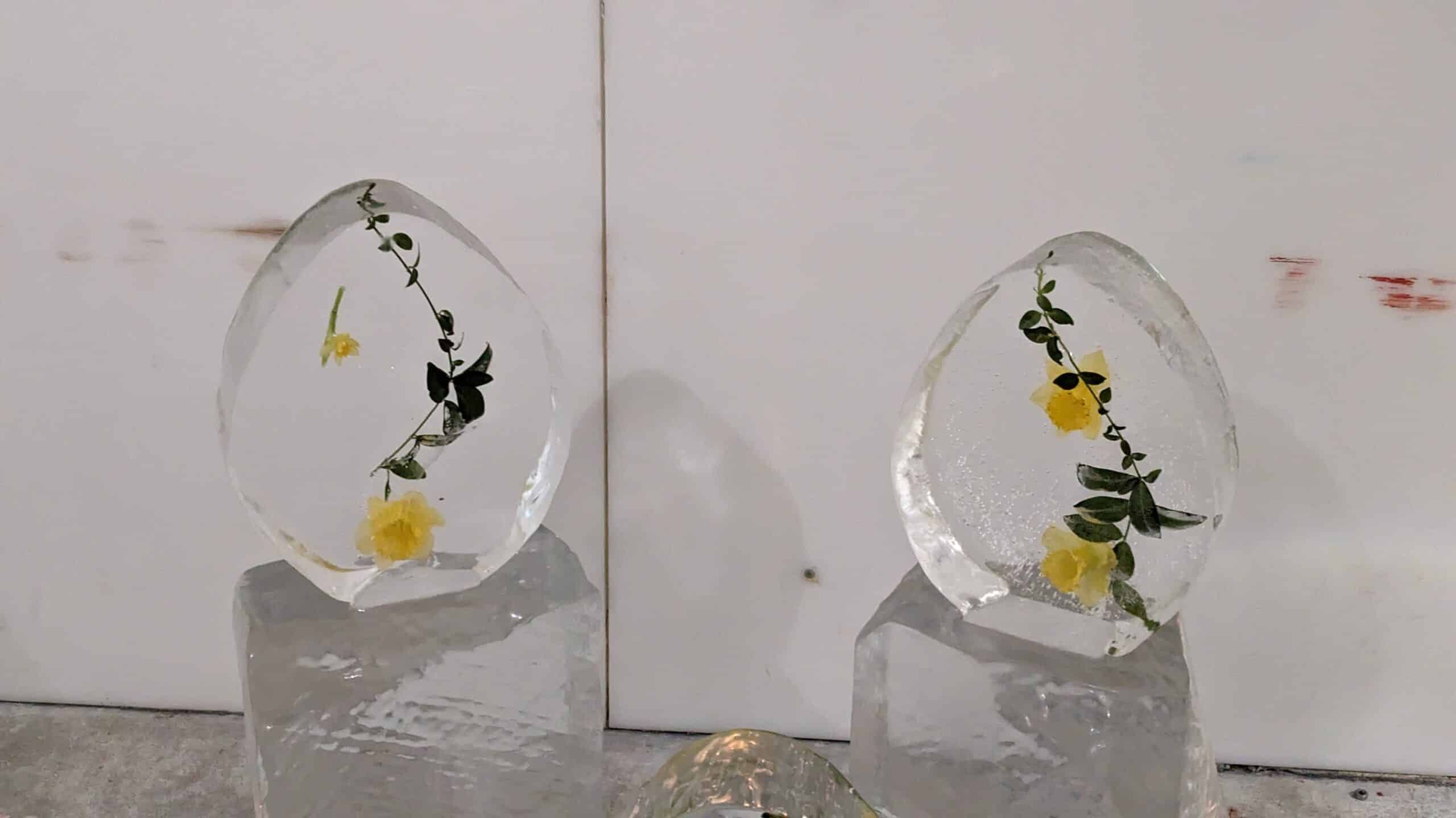 Zwei Eisskulpturen mit gelben Blumen darauf.