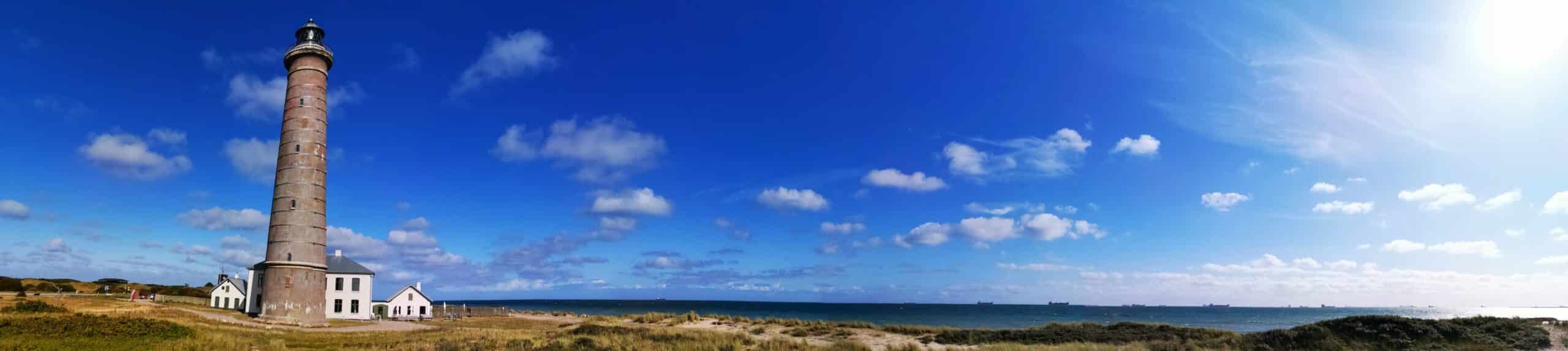 Ein Leuchtturm an einem Strand mit blauem Himmel.
