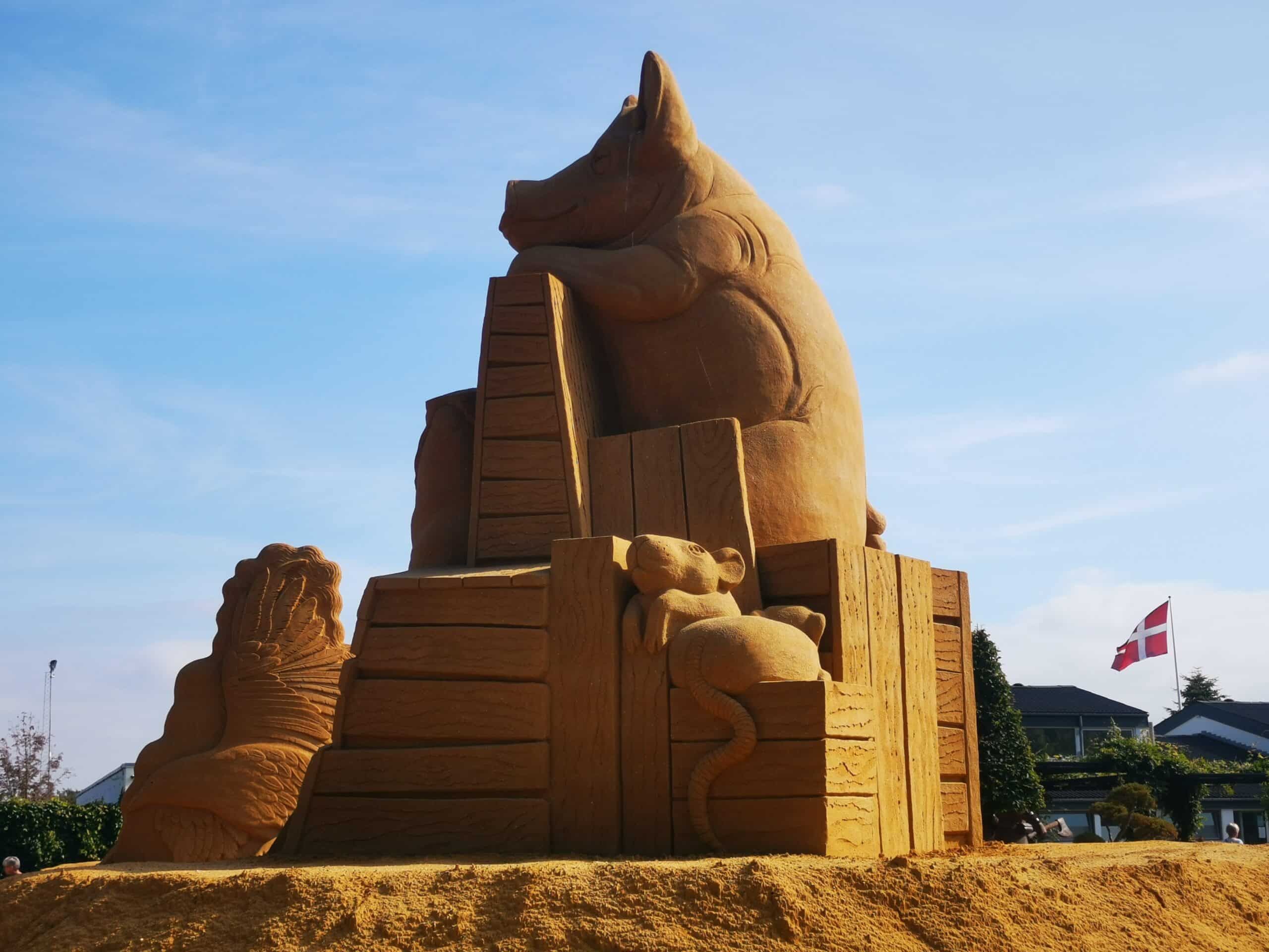 Eine Sandskulptur eines Schweins und eines Hundes.