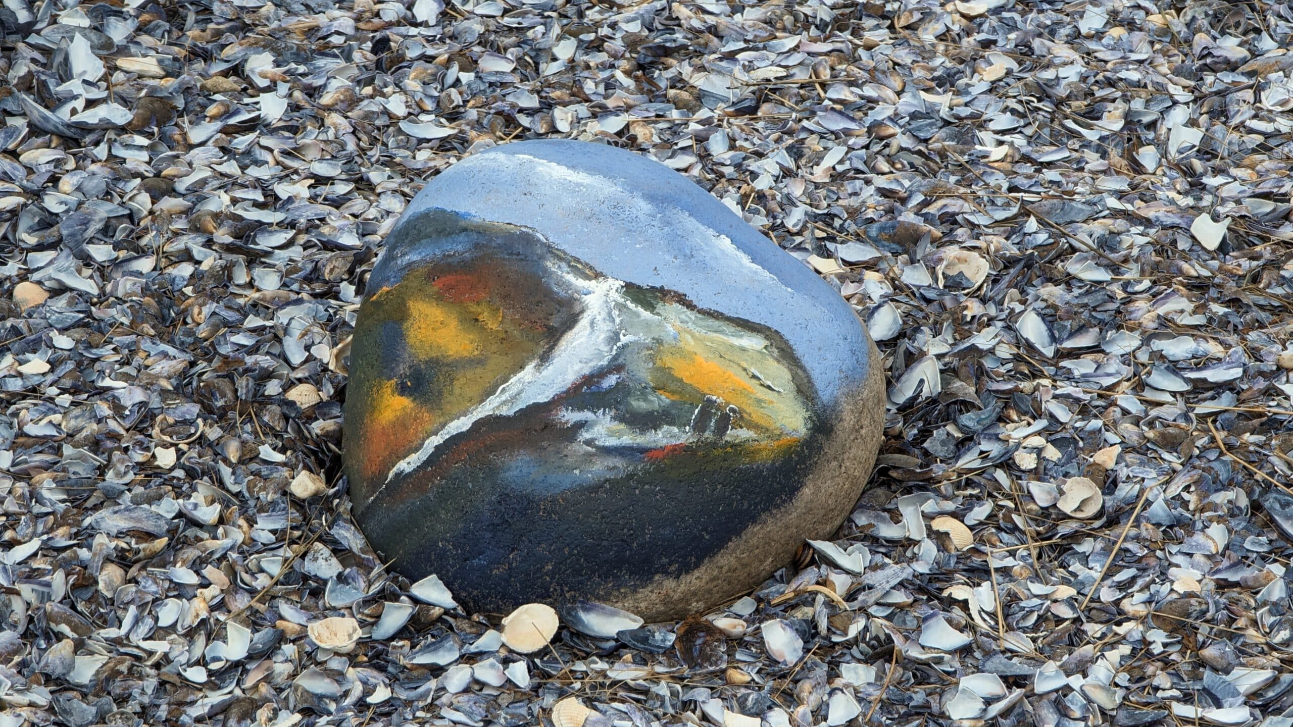 Ein Stein mit einem Gemälde darauf im Sand.