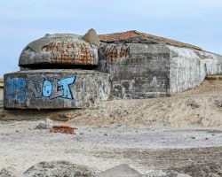 Ein Betonbunker mit Graffiti im Sand.