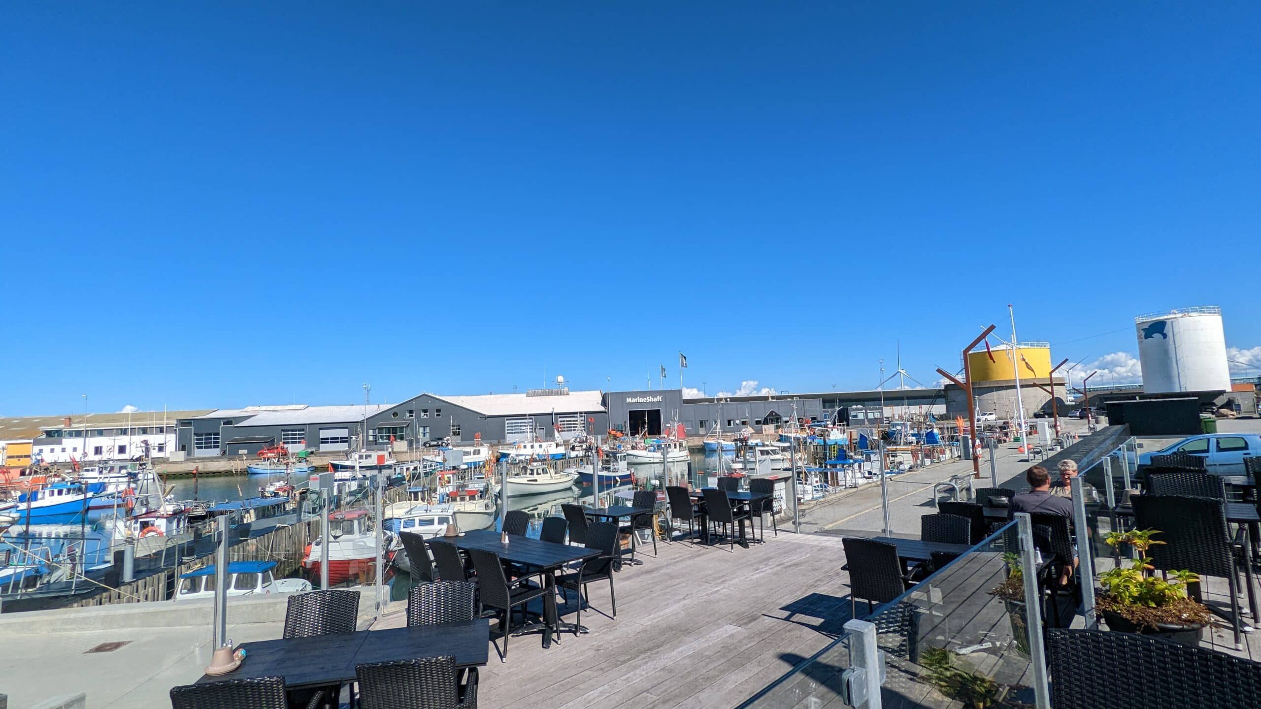 Ein Restaurant mit Tischen und Stühlen mit Blick auf einen Yachthafen.