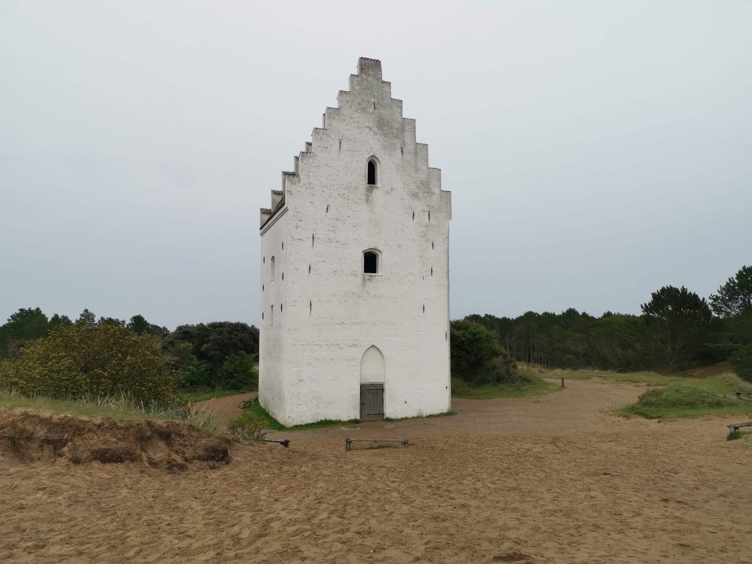 Ein weißer Turm steht auf einem Sandstrand.