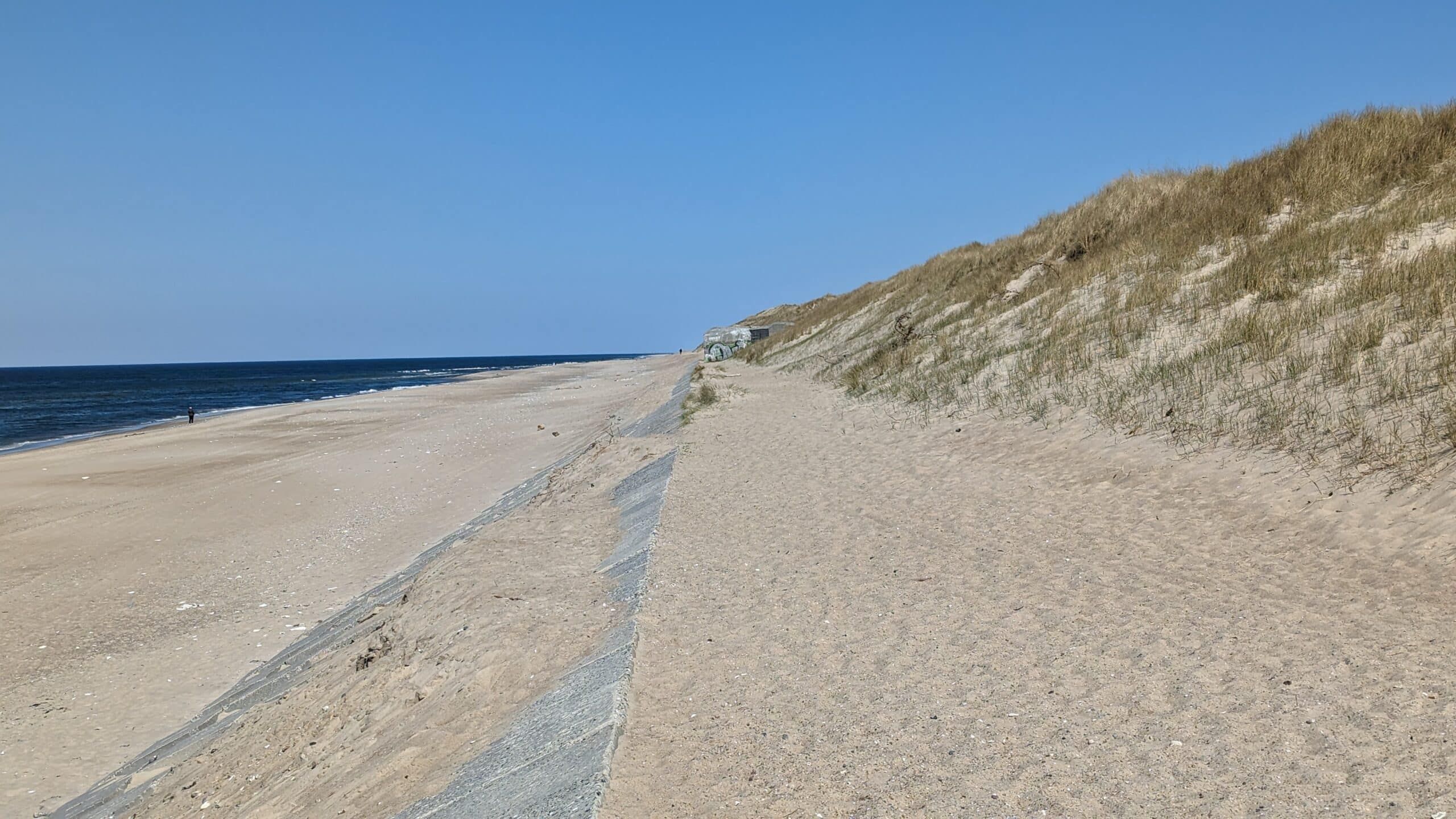 Ein Strand mit einer Sanddüne daneben.