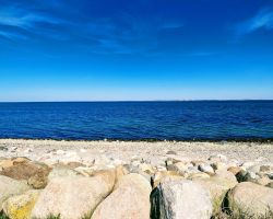 Ein Strand mit Felsen und blauem Himmel.