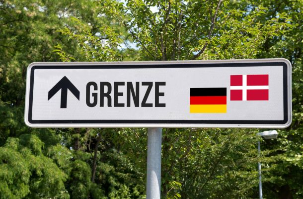 Ein Straßenschild mit Flaggen Dänemarks und Deutschlands.