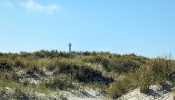Ein Leuchtturm steht auf einer Sanddüne.
