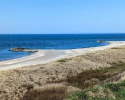 Ein Strand mit Sand und Gras in der Nähe des Ozeans.