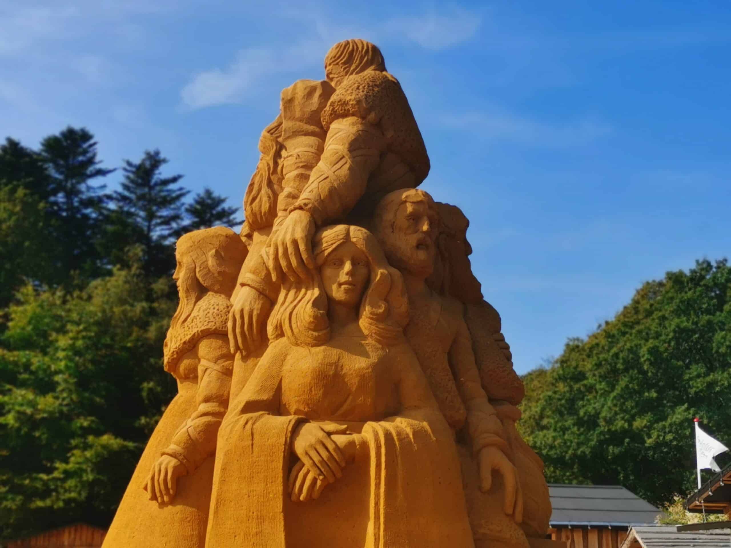 Eine Sandskulptur von Menschen übereinander.