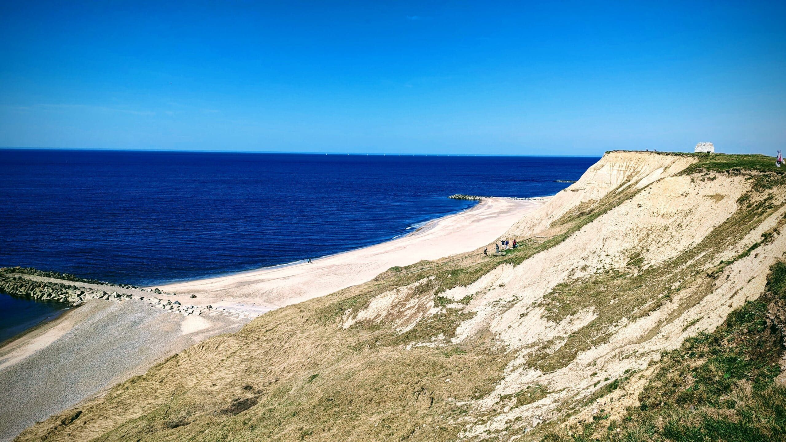 Eine Klippe mit Blick auf das Meer und einen Strand.