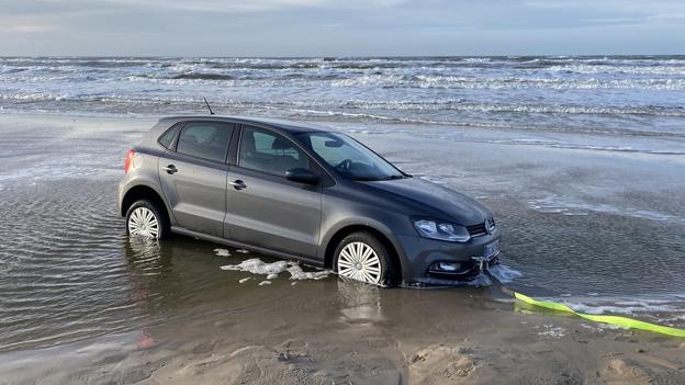 Ein Volkswagen Polo steckt am Strand im Sand fest.
